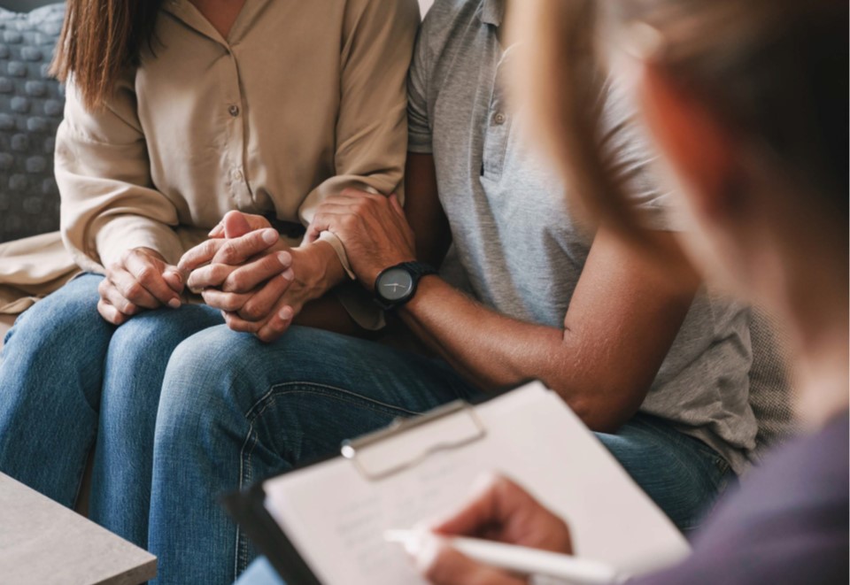 Three people sitting around a table for a therapy session