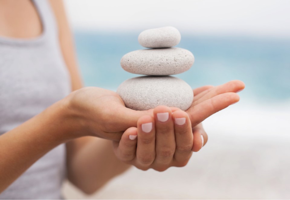 Person holding rocks with the words stress less: relaxation enhancement manuals