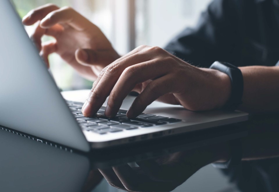 Hands typing on a laptop computer