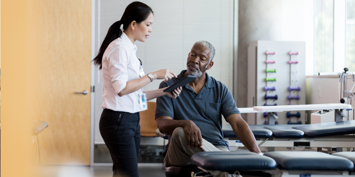 Man near retirement at a physical therapy session reviewing retirement benefits with counselor