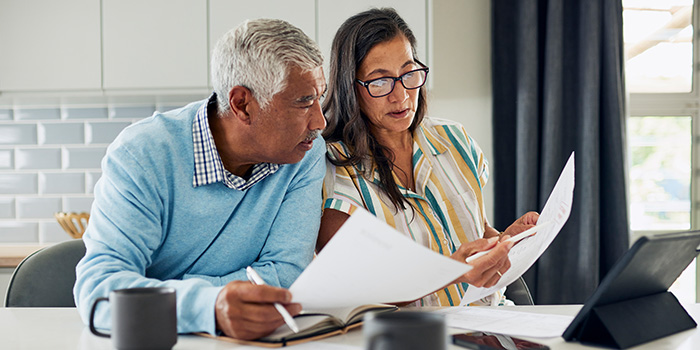 Woman and man reviewing investment options on paper and computer