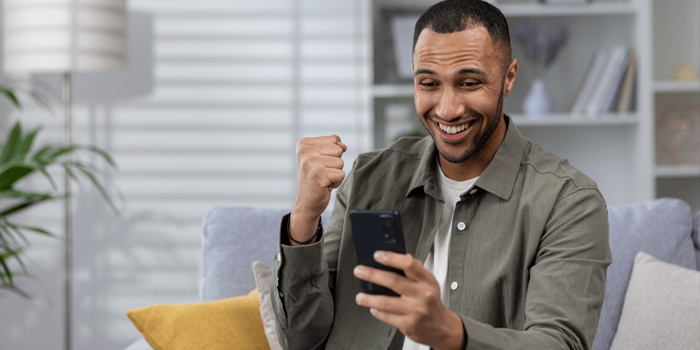 Man seeing how much he has saved in his bank app on phone and celebrating