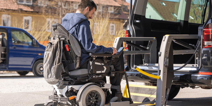 Man in a wheelchair using assitive technolody to get into a vehicle