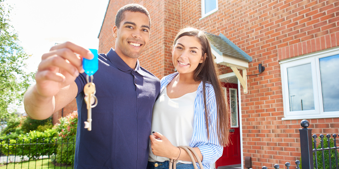 Man and woman in front of their new home with keys