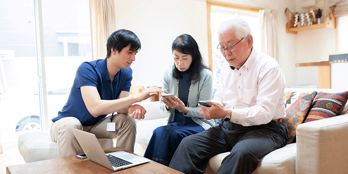 Volunteer helping older woman and man with mobile banking