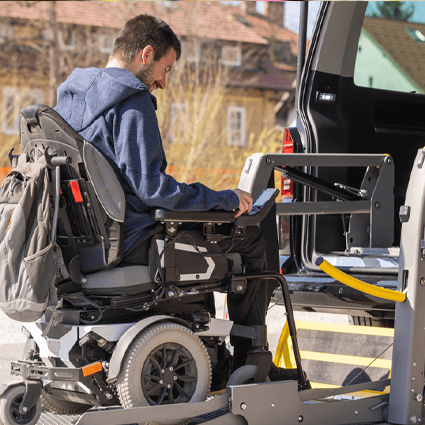 Man in a wheelchair using assitive technolody to get into a vehicle