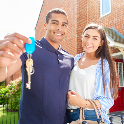 Man and woman in front of their new home with keys