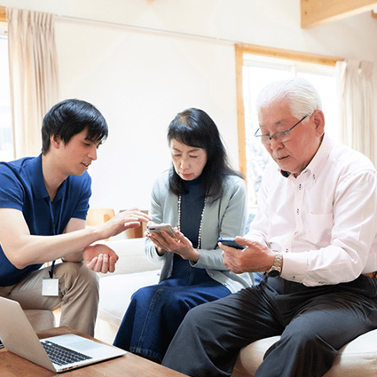Volunteer helping older woman and man with mobile banking