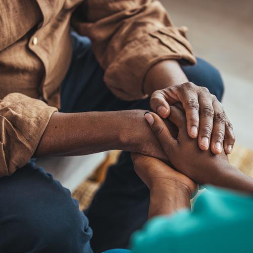 A close up of 2 people holding hands in a warm embrace of loving support for each other.