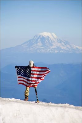 Wounded Warrior holding American flag on snowy mountainside