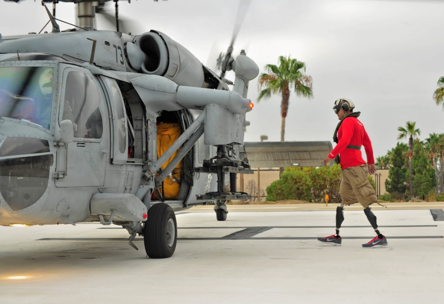 U.S. Marine Wounded Warrior of Naval Medical Center in San Diego, California, walks toward an MH-60S Sea Hawk helicopter assigned to the Blackjacks of Helicopter Sea Combat Squadron (HSC) 21. The Defense Health Agency recently welcomed the Extremity Trauma and Amputation Center of Excellence to lead the advancement of extremity trauma-related research and clinical practice innovations. (Photo: U.S. Navy Mass Communication Specialist Seaman Justin W. Galvin)